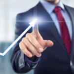 Мужчина в костюме указывает пальцем на стрелку,возрастающую вверх