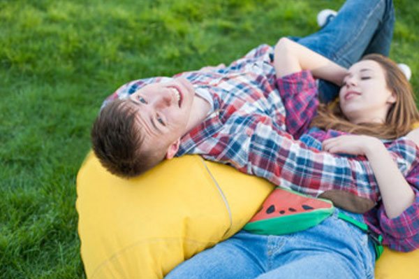 Парень с девушкой лежат вальтом на пуфике на траве